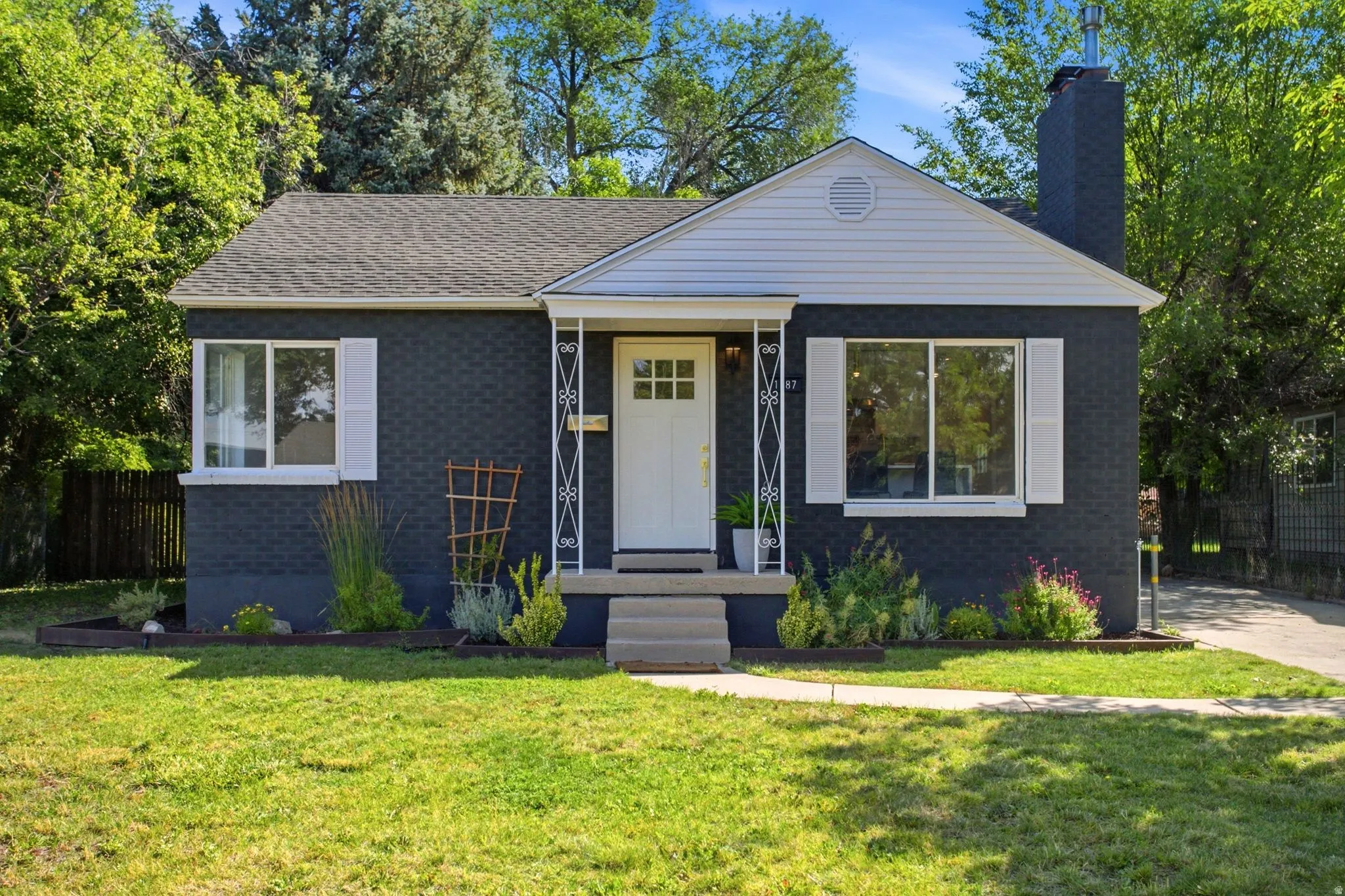 Charming brick ranch home featuring a freshly updated exterior with dark brick facade, crisp white trim, and a welcoming yellow entry door