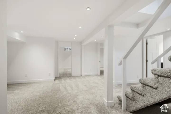 Expansive basement featuring open-concept layout with plush carpeting, recessed ceiling lights, and support columns