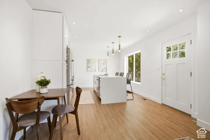 Open-concept living space featuring wood-finish flooring, recessed lighting, and a white kitchen island with a sink and pendant lighting