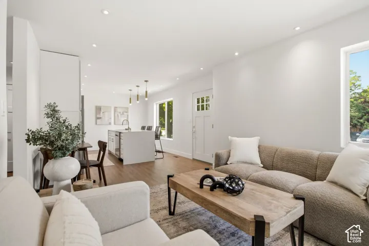Bright, open living space featuring hardwood flooring, recessed ceiling lighting, and large windows with natural light