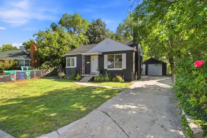 Charming mid-century home featuring a dark exterior with white trim, covered front porch, and large picture windows