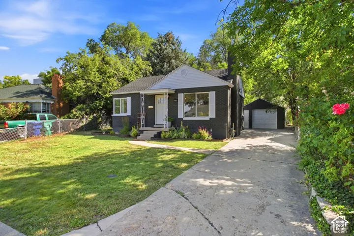 Charming mid-century home featuring a dark exterior with white trim, covered front porch, and large picture windows