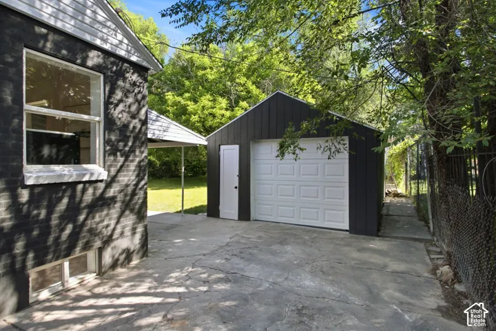 Modern detached garage featuring a white paneled overhead door, black exterior siding, and concrete apron