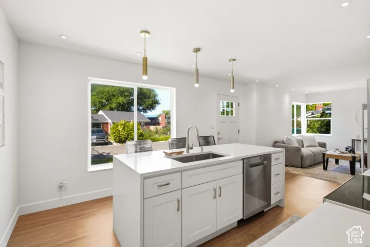 Contemporary kitchen island featuring a stainless steel sink with a high-arc faucet, quartz countertop, and white shaker cabinetry