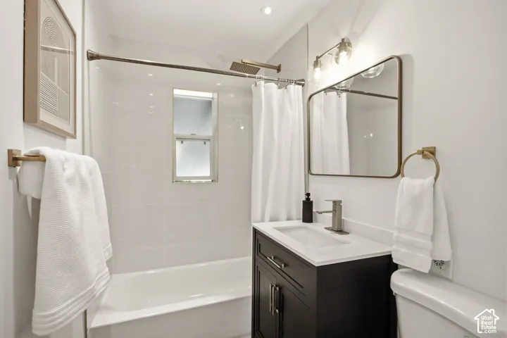 Bathroom featuring a white subway tile tub surround, dark wood-finish vanity with a white countertop, and brushed nickel fixtures