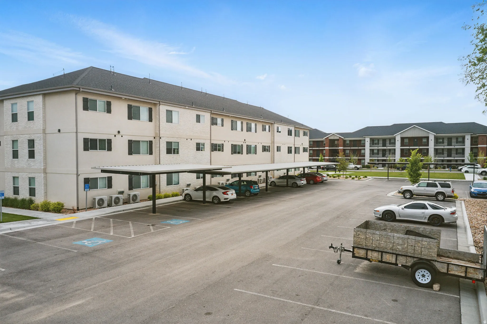 Modern multi-unit residential building featuring a clean cream and charcoal exterior with symmetrical fenestration across three stories