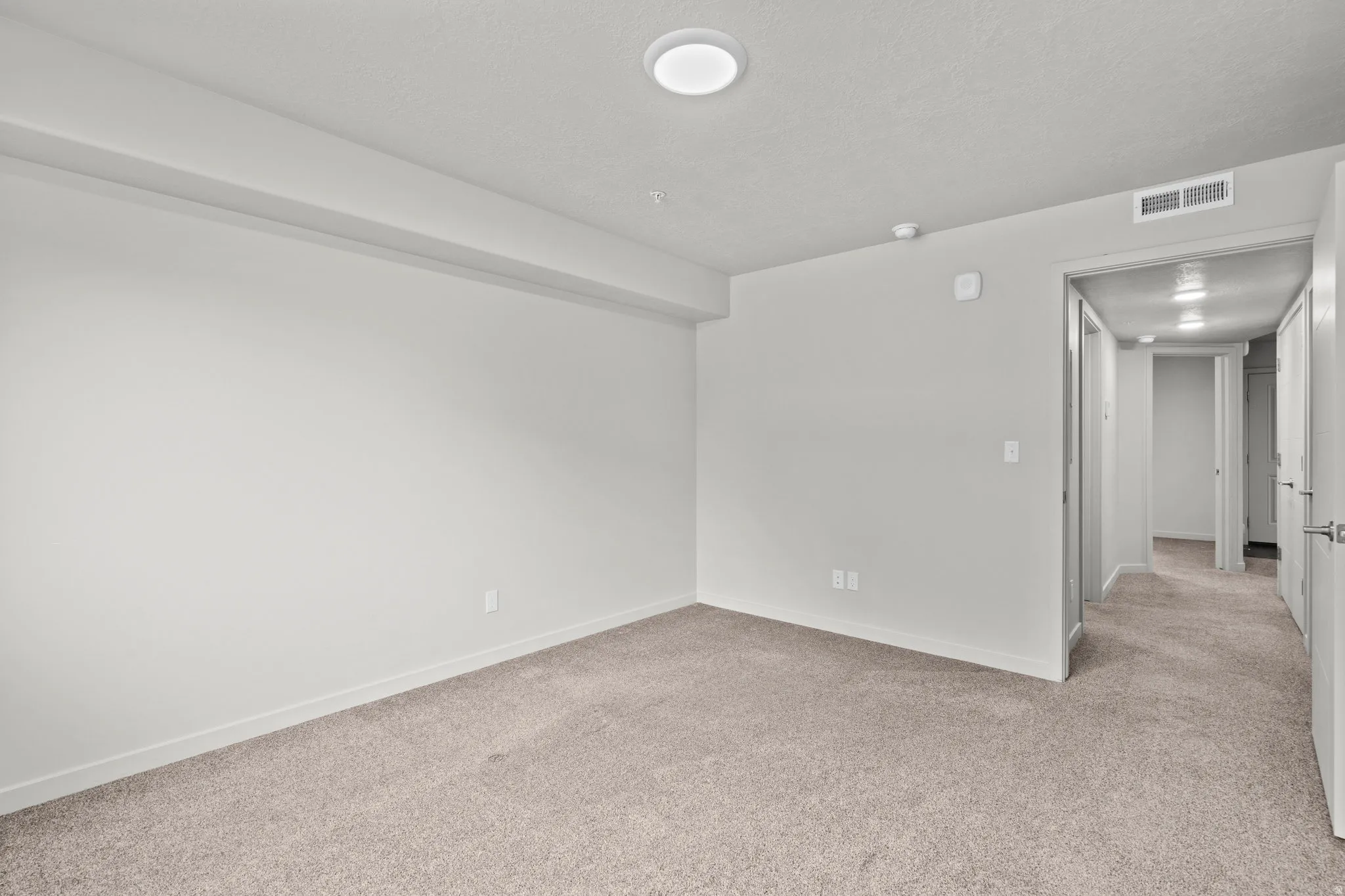 Spacious bedroom featuring neutral wall finishes, recessed ceiling lighting, and soft neutral carpet flooring