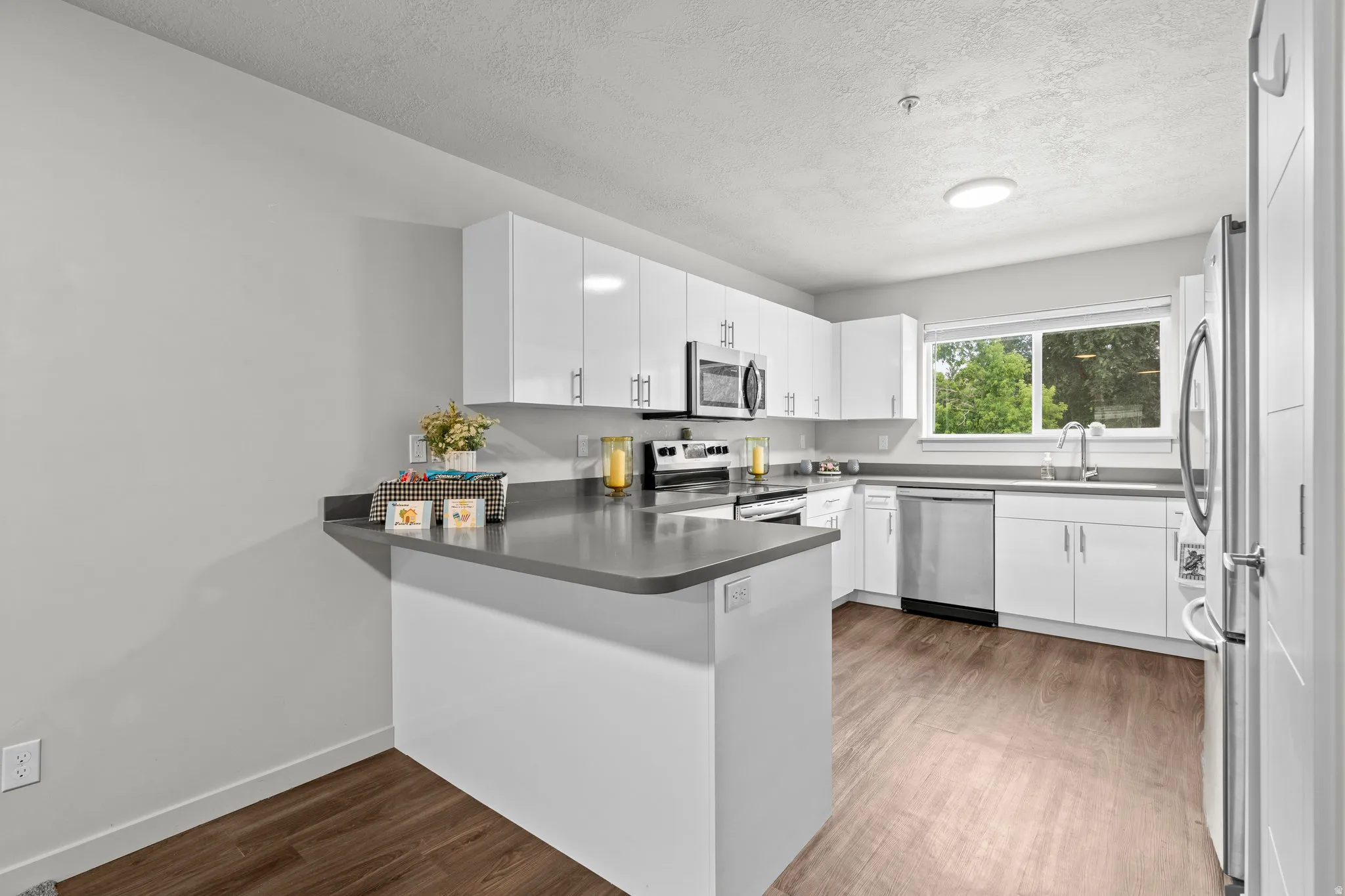 Modern kitchen featuring white cabinetry with stainless steel hardware, quartz countertops, and a center island with breakfast bar seating