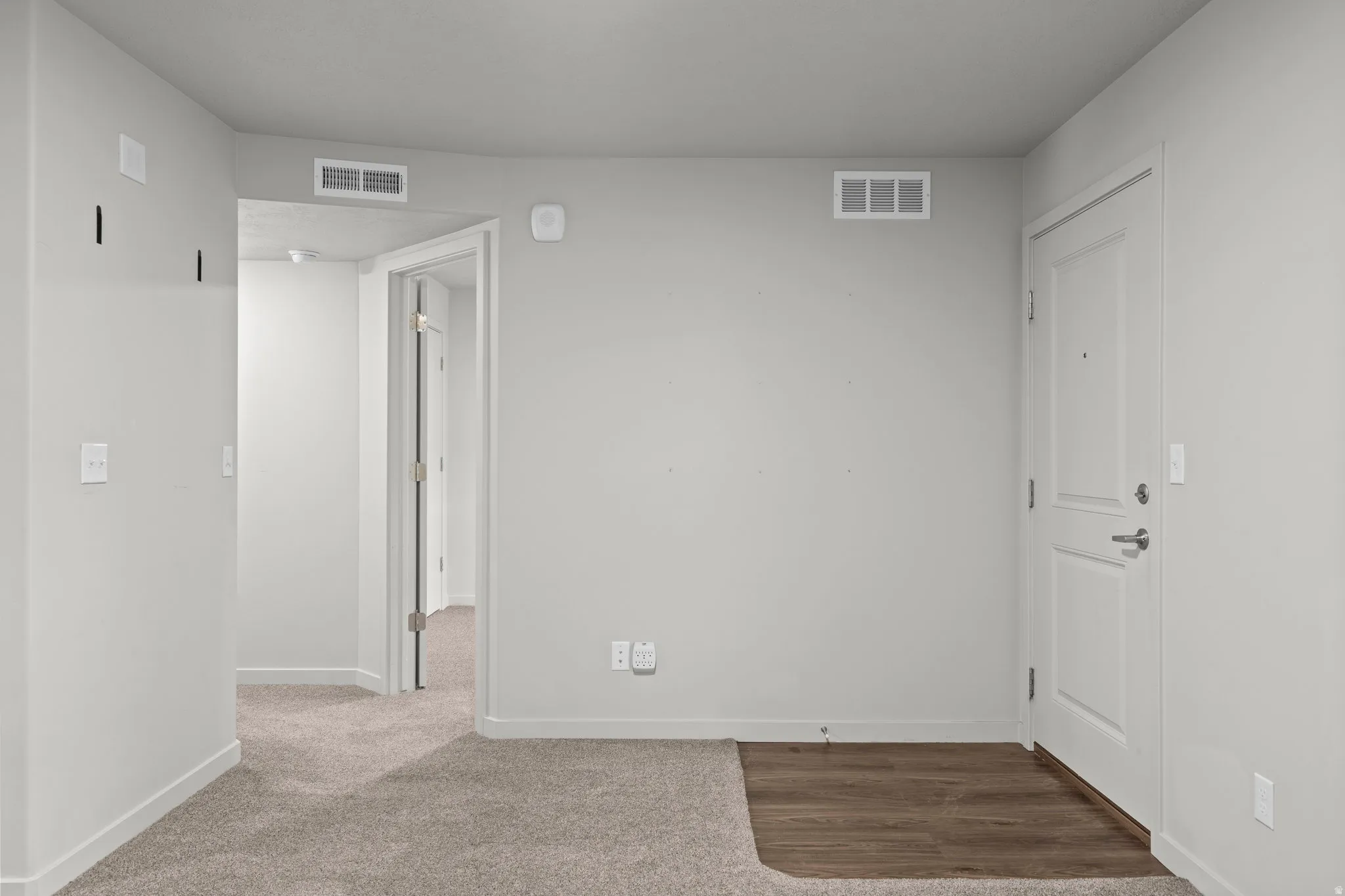 Entryway featuring light gray wall paint, white trim, wood-finish flooring, and a panel-style door with brushed nickel hardware