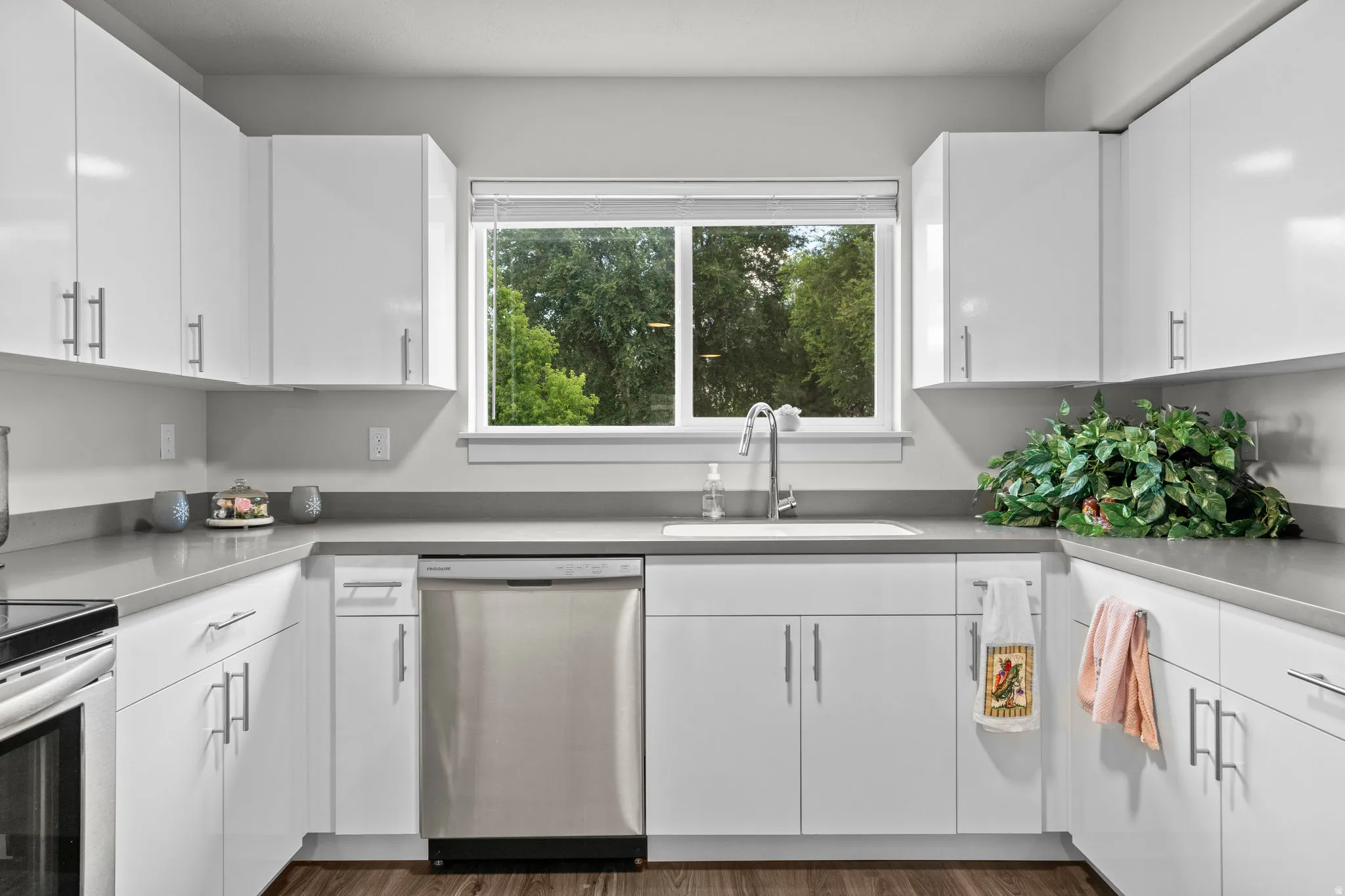 Modern kitchen featuring crisp white cabinetry with stainless steel hardware, a stainless steel dishwasher, and a polished undermount sink