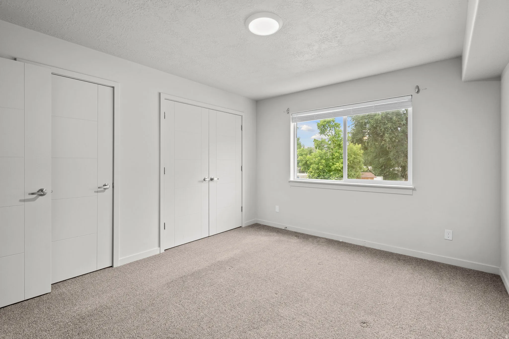 Carpeted room with a rectangular window and two sets of double-panel closet doors