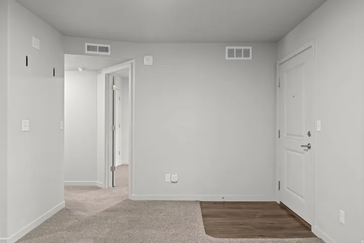 Entryway featuring light gray wall paint, white trim, wood-finish flooring, and a panel-style door with brushed nickel hardware