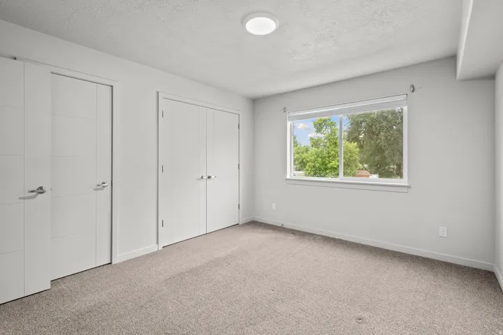 Carpeted room with a rectangular window and two sets of double-panel closet doors