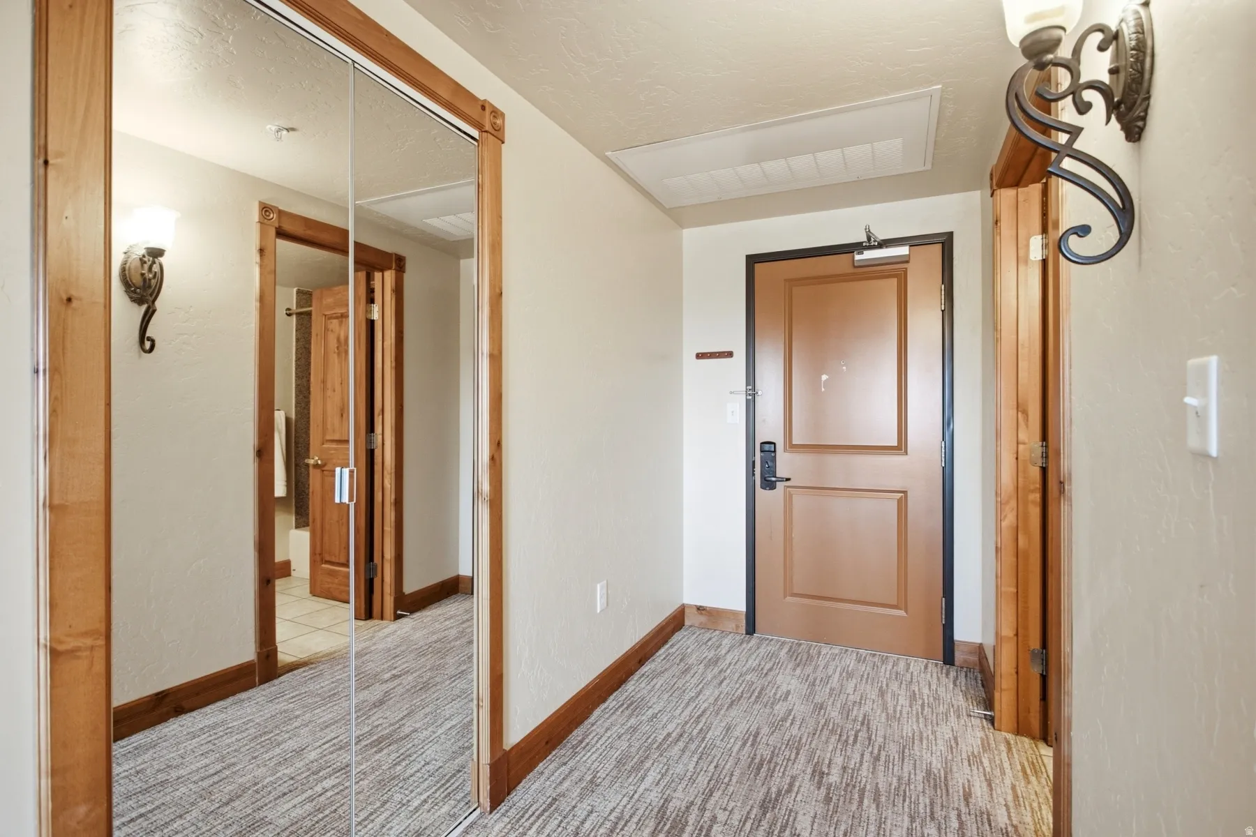 Welcoming foyer featuring warm wood-trimmed architectural details, neutral wall finishes, and a blend of natural and recessed lighting