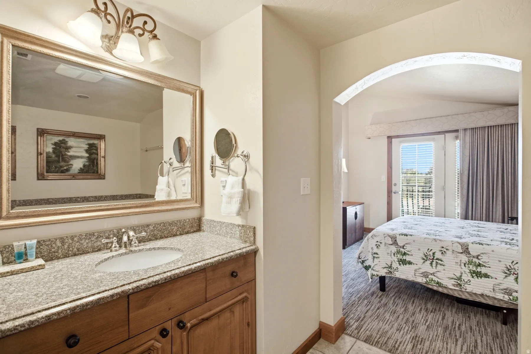 Bathroom vanity featuring a polished stone countertop, undermount sink, and wood-finish cabinetry