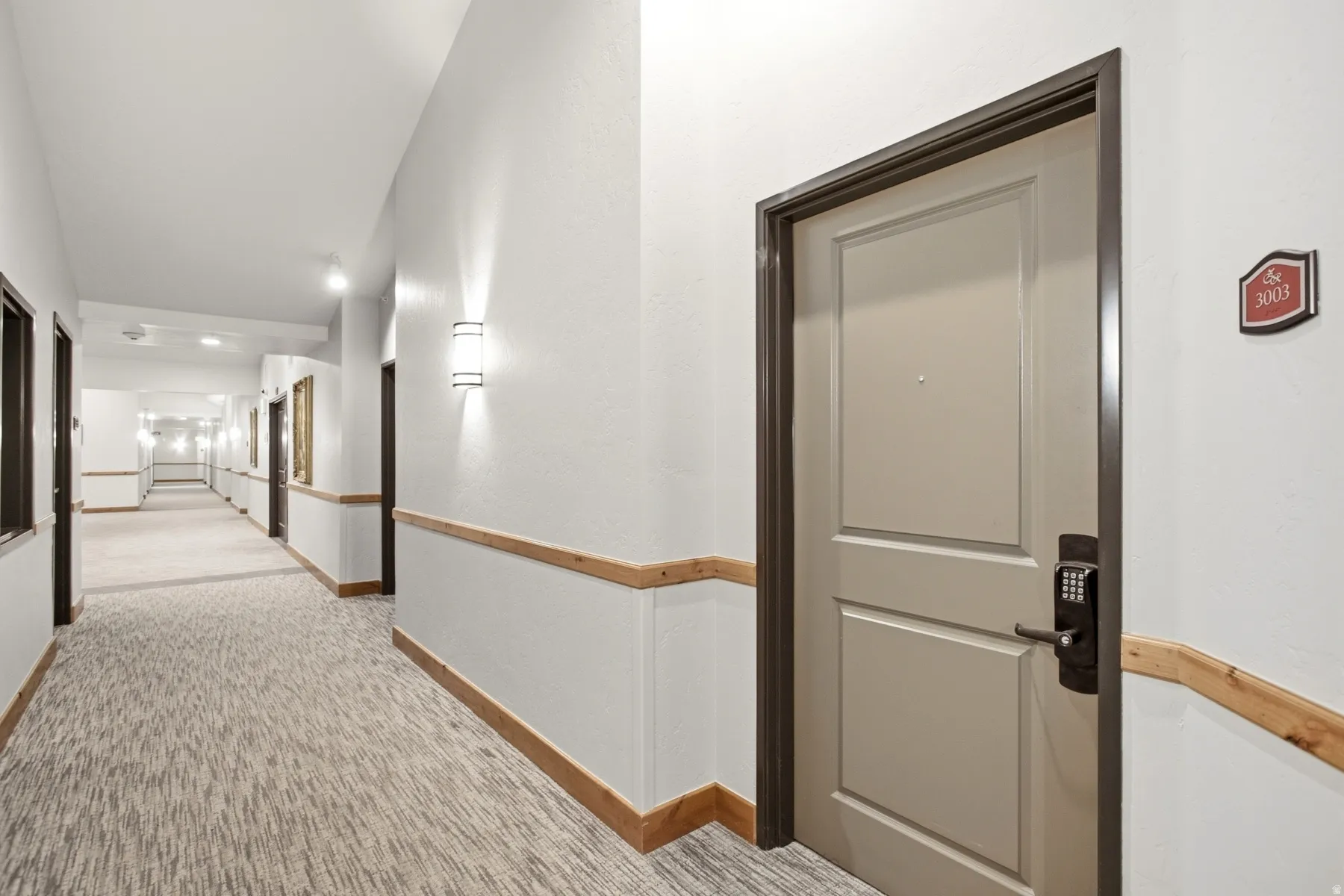 Well-appointed hallway featuring recessed ceiling lighting, wood-finish handrail, neutral wall finishes, and direct access to elevator and stairwell