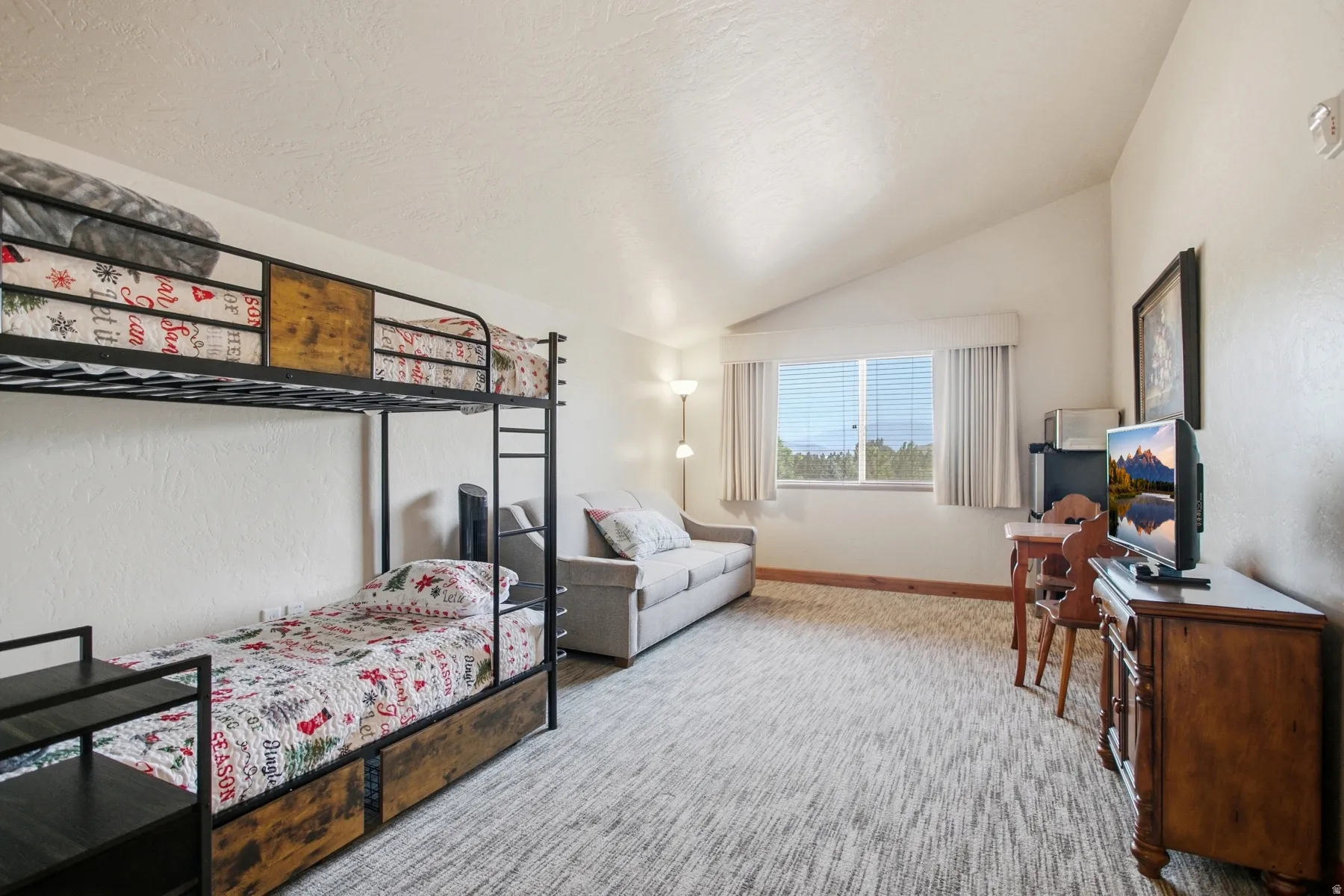 Spacious bedroom featuring dual bunk beds with wood-finish frames, plush bedding, and coordinating storage