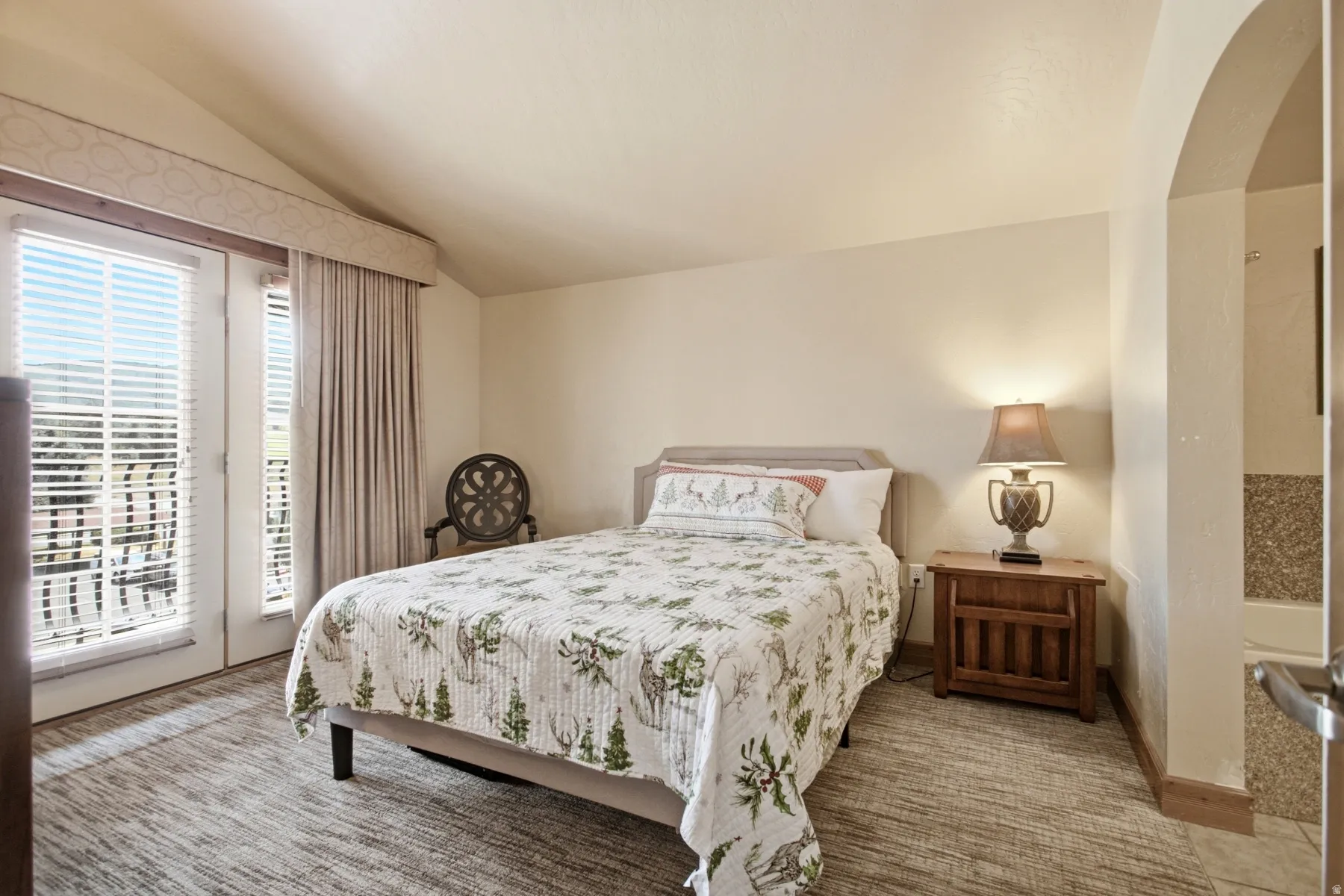Serene bedroom retreat featuring a queen bed, wood-finish nightstand with attached lighting, and large glass sliding doors opening to a private balcony
