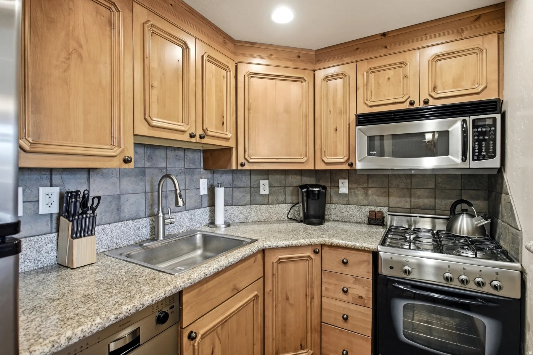 Kitchen featuring wood cabinetry, stone-finish countertops, and a tiled backsplash