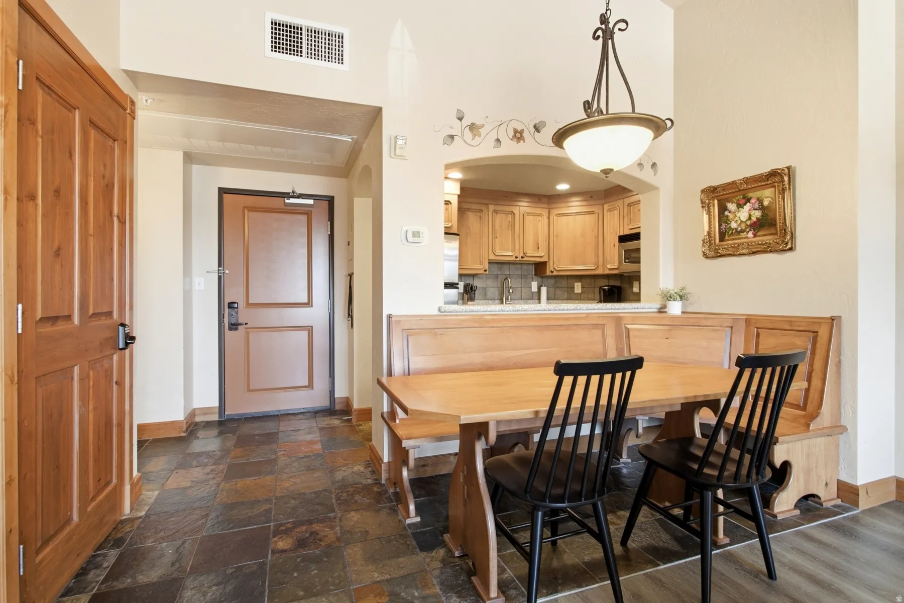 Open dining area featuring a built-in wooden banquette, an arched pass-through to the kitchen, and a wrought iron chandelier