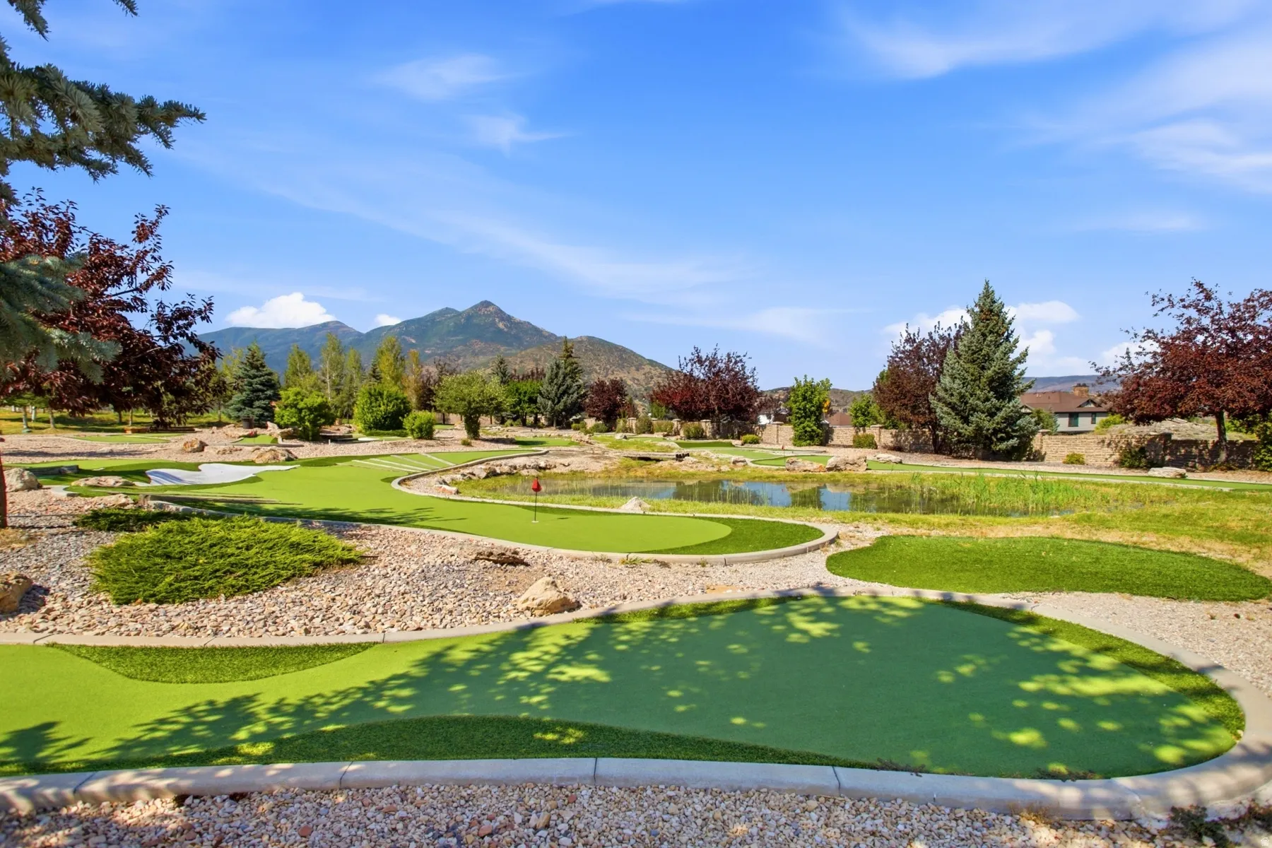 Scenic property grounds featuring a professionally designed mini golf course with multiple putting greens, manicured fairways, and natural stone edging