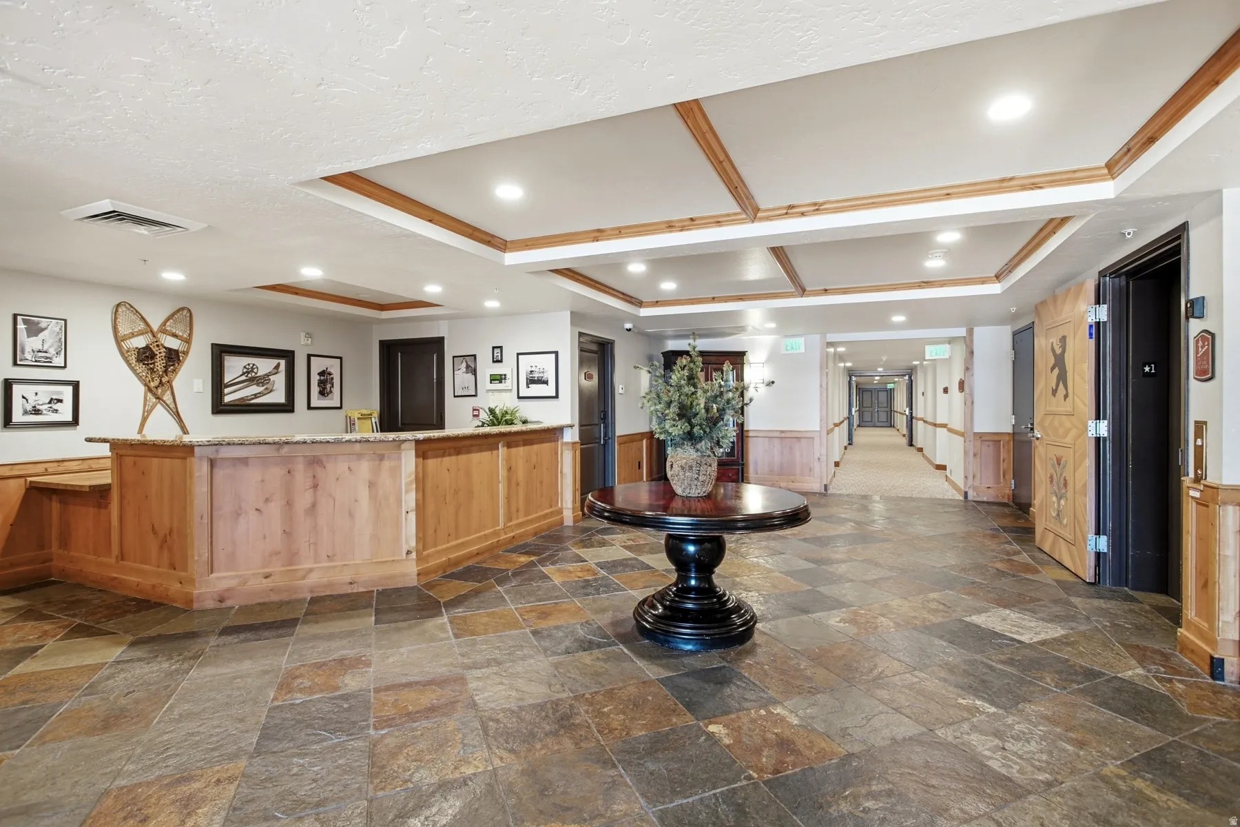 Spacious entryway featuring stone-finish floor tiles and a wood-paneled reception desk with a stone countertop