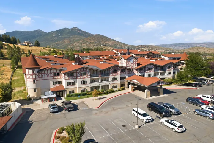 Alpine-style resort property featuring distinctive half-timbered architectural detailing with terracotta tile roofing, multi-level construction with cream and white exterior finishes, and expansive paved parking area