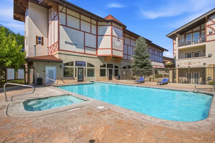 Outdoor swimming pool featuring a connected spa, surrounded by stamped concrete decking and a perimeter fence