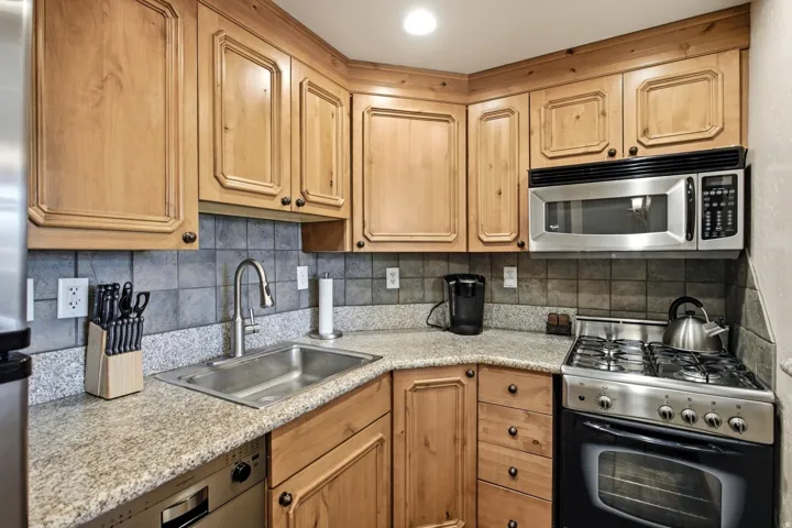 Kitchen featuring wood cabinetry, stone-finish countertops, and a tiled backsplash