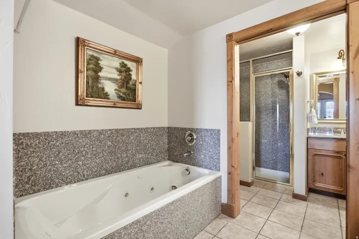 Soaking tub with jetted features, surrounded by a stone-finish tile wainscoting