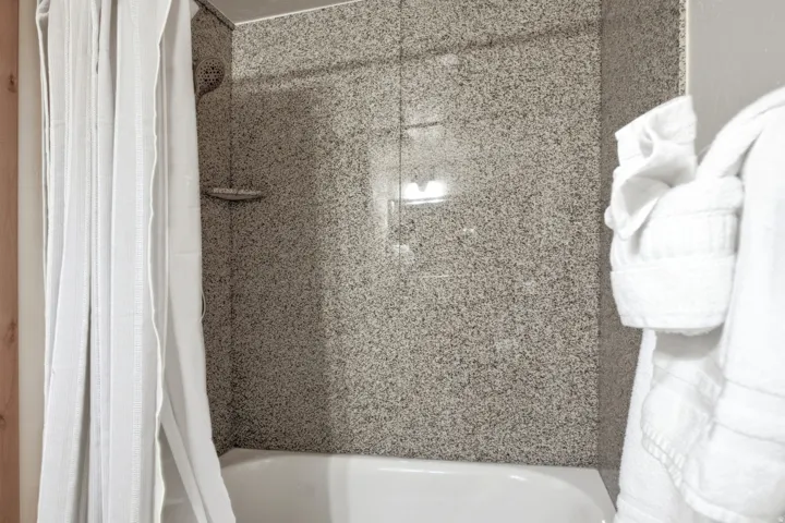 Bathtub with a speckled shower surround and a wall-mounted showerhead