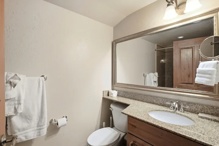 Modern bathroom featuring a wood-finish vanity with dual-sink configuration, granite countertop, and chrome fixtures