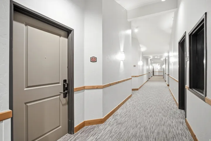 Well-appointed hallway featuring clean white walls, recessed ceiling lighting, and a continuous wood-finish handrail