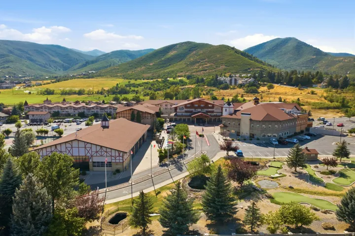 Modern commercial or mixed-use property featuring expansive copper-toned metal-clad structures with pitched rooflines, situated on manicured grounds with mature coniferous landscaping