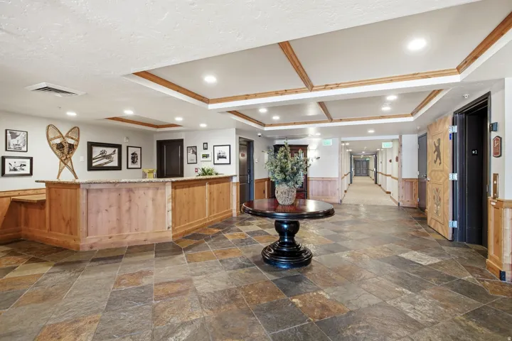 Spacious entryway featuring stone-finish floor tiles and a wood-paneled reception desk with a stone countertop
