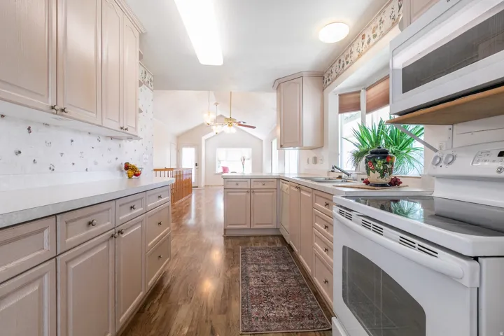 Kitchen featuring light-toned cabinetry, pull out shelves, light countertops, Pantry, and wood-finish flooring