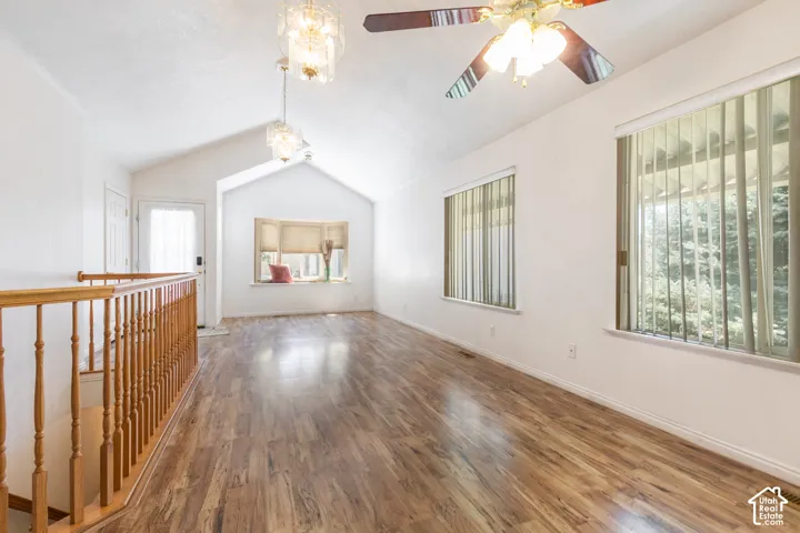Spacious, open room featuring vaulted ceilings, wood-finish flooring, and window seat, vertical blinds, open living, dining & Kitcheen. Ceiling Fan and Chanldeliers.