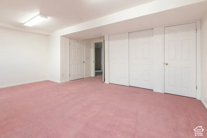 Spacious room featuring wall-to-wall carpeting, multiple white panel doors, and overhead fluorescent lighting