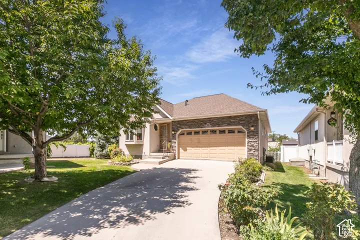 Exterior featuring a concrete driveway, attached garage with a dual door, stucco siding, and stone accents