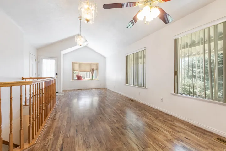 Spacious, open room featuring vaulted ceilings, wood-finish flooring, and window seat, vertical blinds, open living, dining & Kitcheen. Ceiling Fan and Chanldeliers.