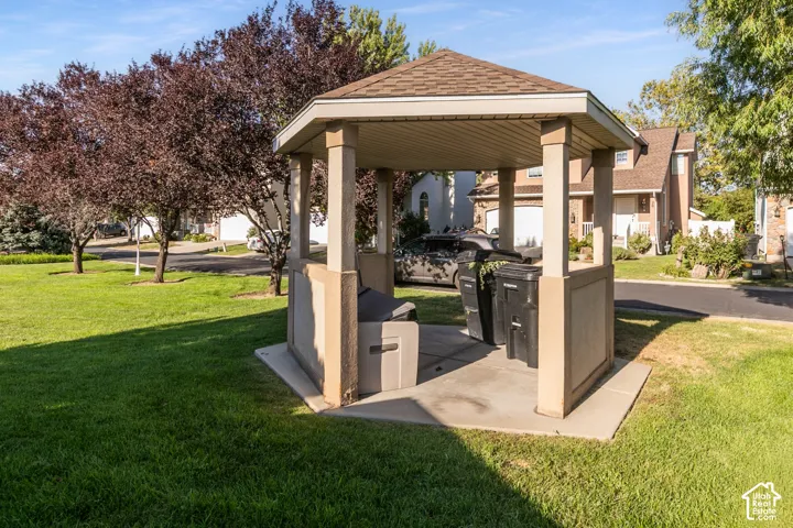 Outdoor covered gazebo with and BBQ surrounded by a manicured lawn and mature trees