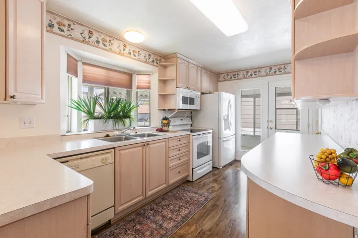 Kitchen featuring greenhouse window with deep integrated sink, wood-finish flooring, and light wood cabinetry