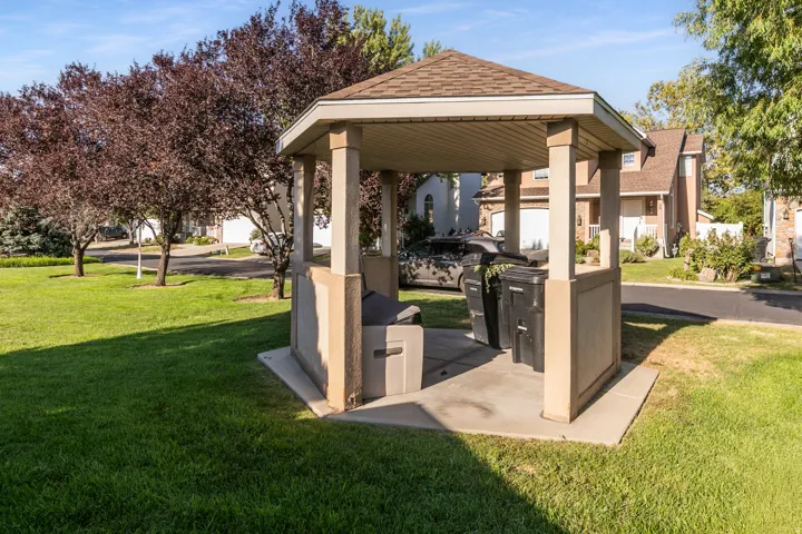 Outdoor covered gazebo with and BBQ surrounded by a manicured lawn and mature trees