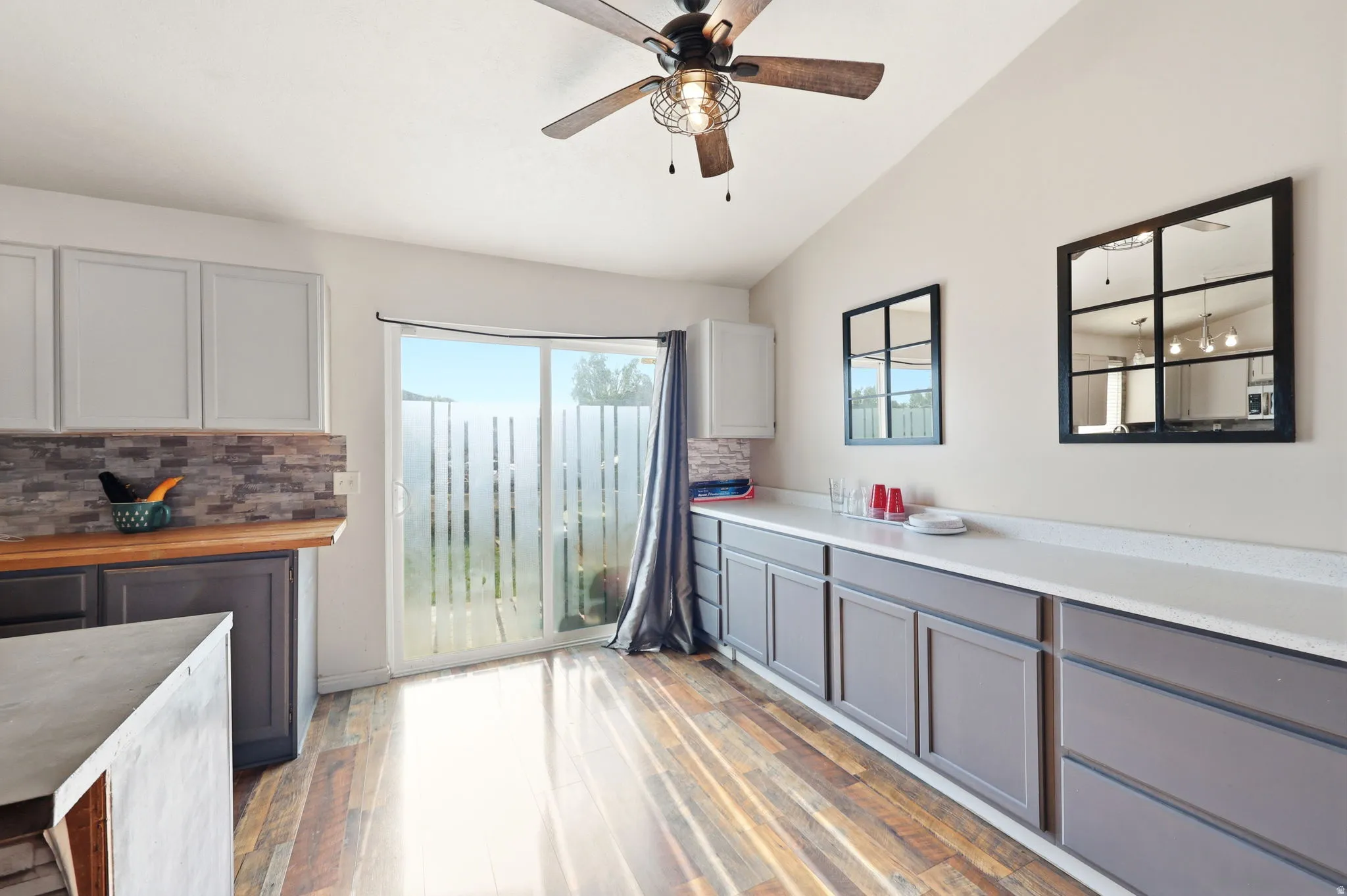 Kitchen area with vaulted ceiling, wood-finish flooring, and a ceiling fan