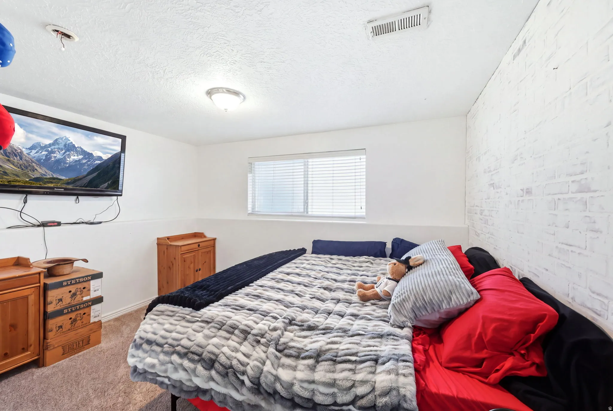 Room featuring white walls, a single window with blinds, and a textured white brick accent wall