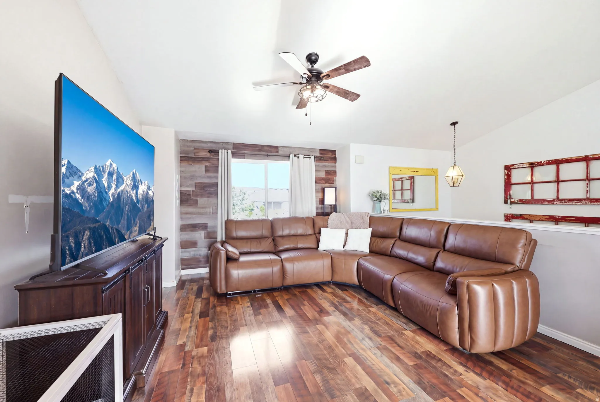 Spacious living room featuring a leather sectional sofa with power recline functionality, wood-finish flooring throughout, and abundant natural light from large windows