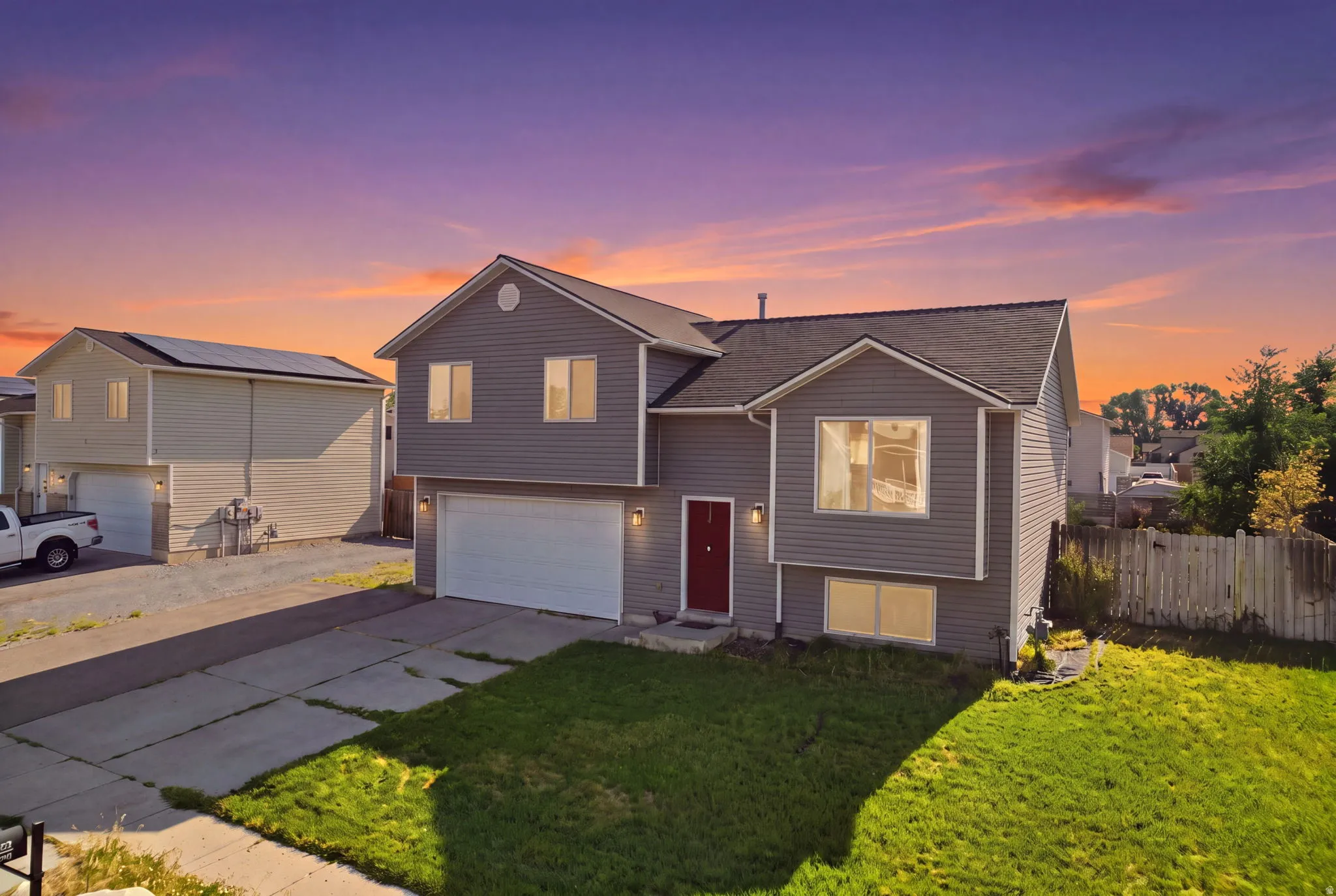 Modern two-story home featuring a charcoal fiber cement exterior with dimensional siding, a prominent two-car garage with paneled doors, and a welcoming red entry door