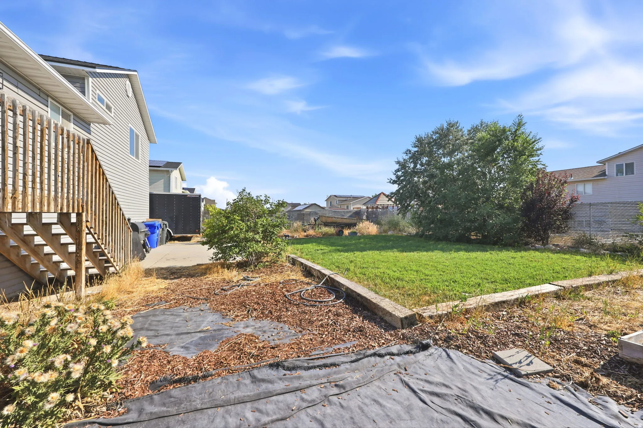 Expansive backyard featuring a generous lawn area, mature landscaping, and established trees