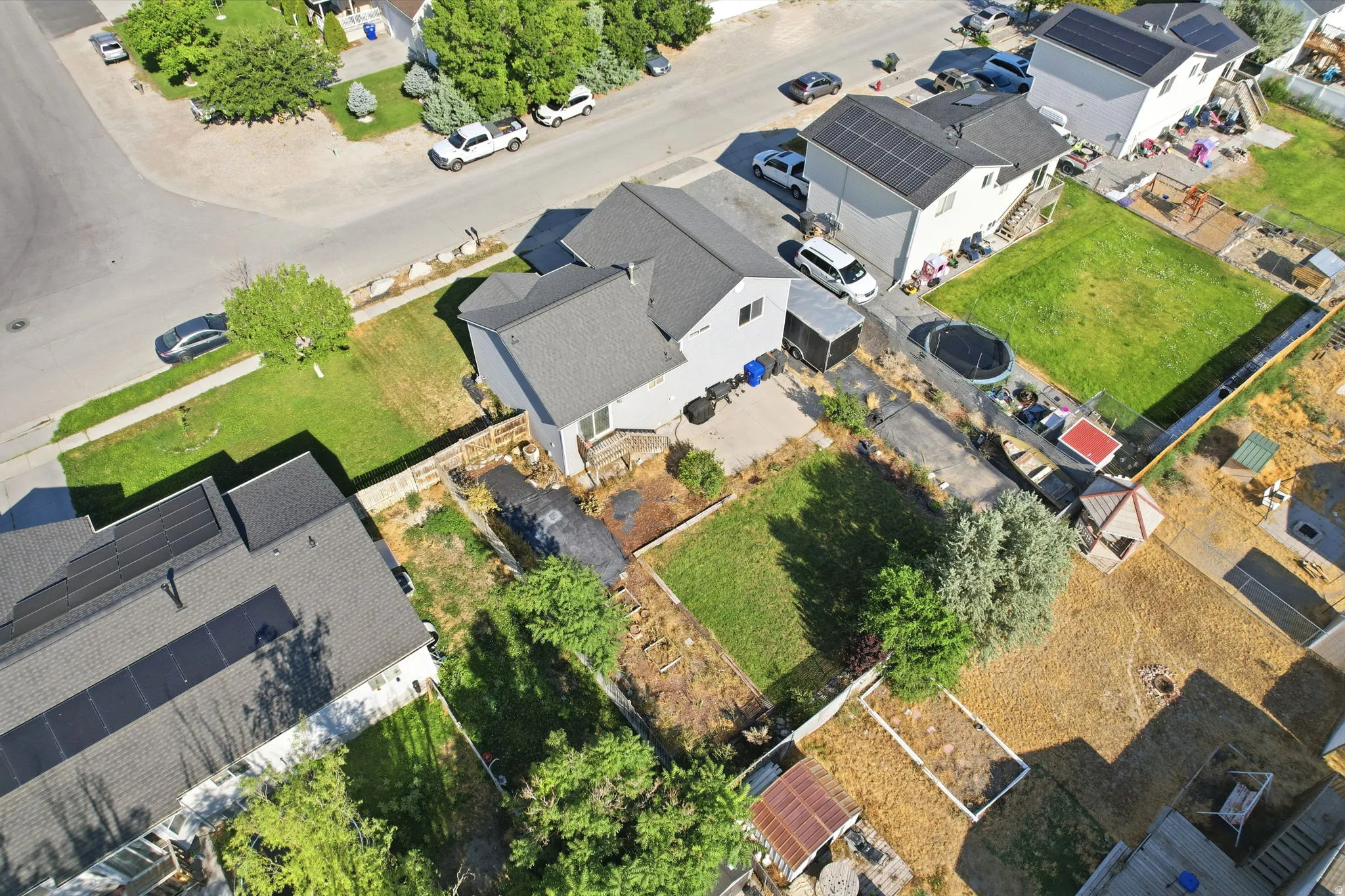Aerial perspective showcasing the property's expansive lot with a grass lawn, mature trees, and a paved driveway