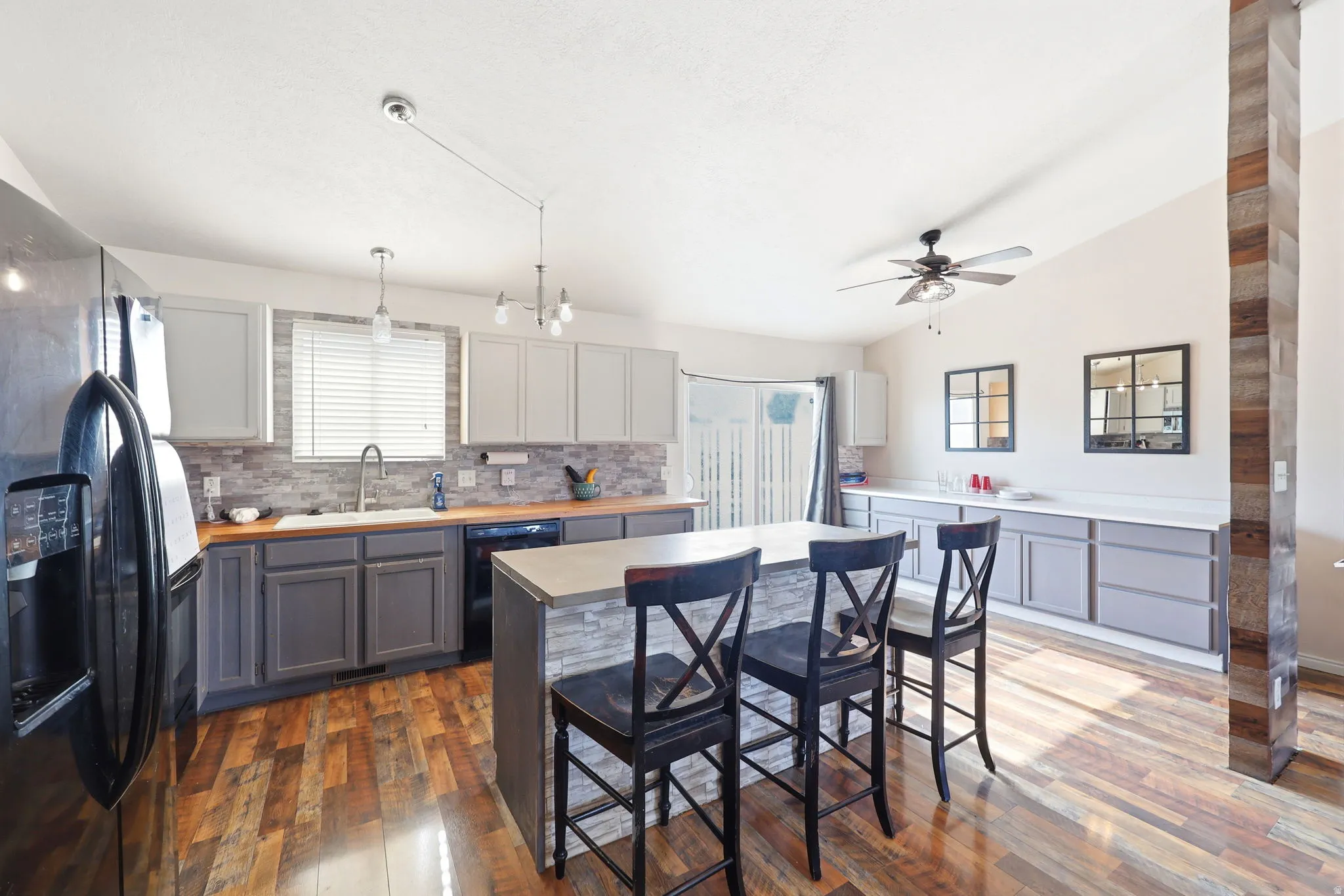 Gourmet kitchen featuring custom cabinetry with gray painted finishes, wood-finish countertops, stainless steel appliances, and pendant lighting